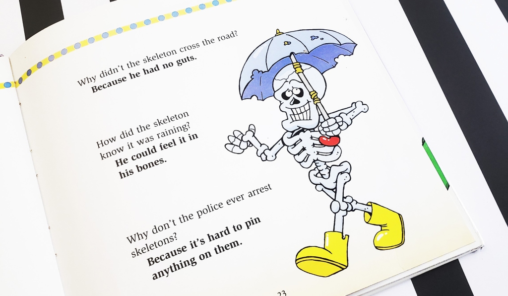 Text next to a happy skeleton with an umbrella illustration reads, "Why didn't the skeleton cross the road? Because he had no guts. How did the skeleton know it was raining? He could feel it in his bones. Why don't the police ever arrest skeletons? Because it's hard to pin anything on them.